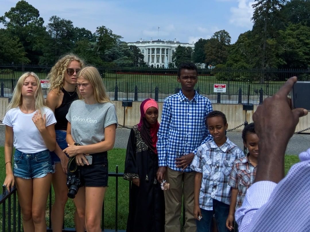 Seven people stand in front of the White House