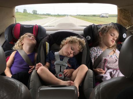 Three children in the back seat of a car, all asleep